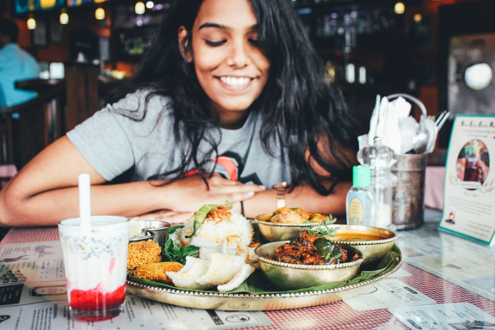 The key to contentment is gratitude - a woman is smiling in front of her meal