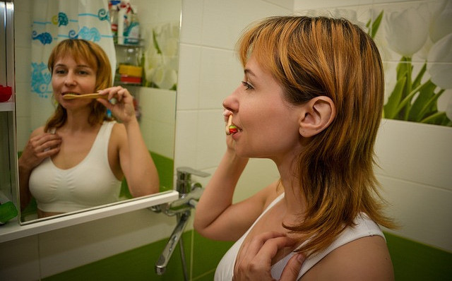What is the secret to Law of Attraction? A woman is brushing her teeth
