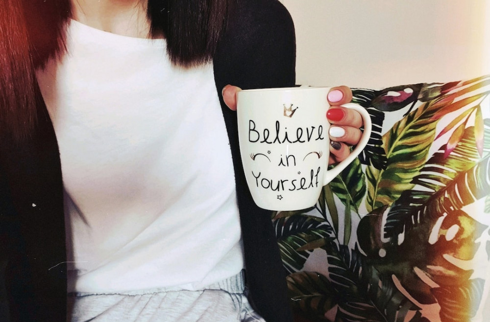 Crystals Help with Manifestation: picture of a woman holding a cup with the line" believe in yourself"