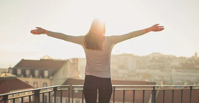 10 healthy ways to relieve stress: a woman is enjoy the sunshine on a balcony