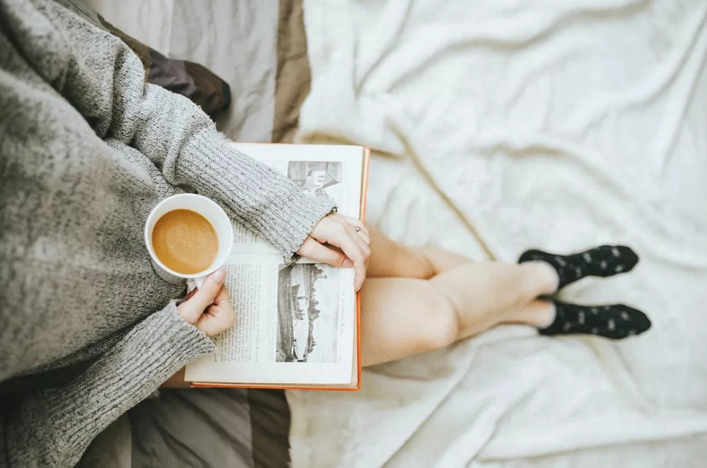 10 healthy ways to relieve stress: a woman is reading book and drinking coffee