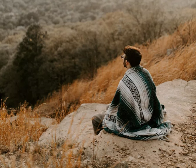 What is the proper way to meditate? a man is sitting comfortably in nature