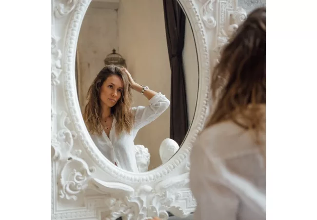 The Law of Attraction on Weight Loss: a woman looking at herself in the mirror