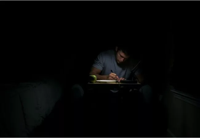 how to start gratitude journaling: a man is writing gratitude journal at night